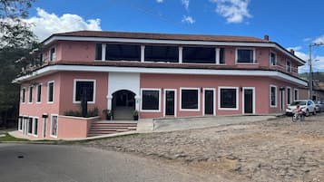 Um edifício de dois andares com telhado de telhas vermelhas, várias janelas e uma escadaria que leva à entrada.