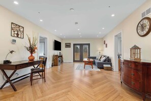 A spacious living room with a wooden floor, a sofa set, a TV mounted on the wall, and a dining area with a table and chairs. - Nordhaus | Walk to Beach | Hot Tub | Private Yard! (South Haven)