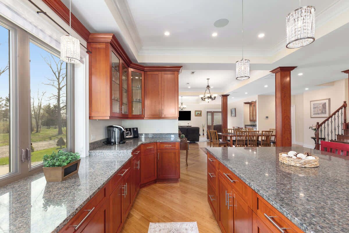 A spacious kitchen with granite countertops, wooden cabinets, and a central island.