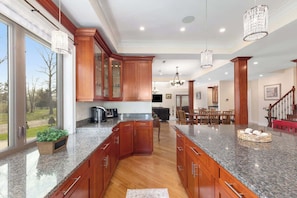 A spacious kitchen with granite countertops, wooden cabinets, and a central island. - Nordhaus | Walk to Beach | Hot Tub | Private Yard! (South Haven)