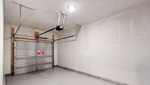 A garage with a white door, metal shelving, and a ceiling-mounted projector. - LakeView Modern 3BR/3BA Near Beach NewBuild Home Myrtle Beach (Myrtle Beach)