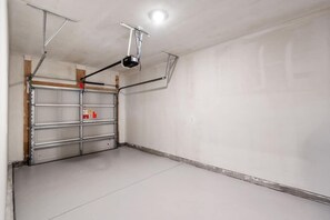 Eine Garage mit weißer Tür, Metallregalen und einem an der Decke befestigten Projektor.