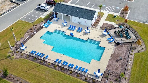 An aerial view of a hotel with a swimming pool, lounge chairs, and a playground. - LakeView Modern 3BR/3BA Near Beach NewBuild Home Myrtle Beach (Myrtle Beach)