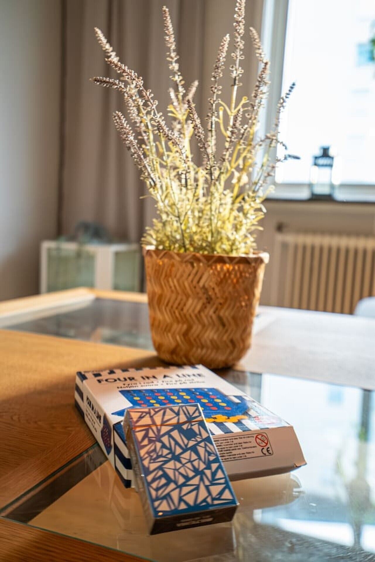 Een kamer met een glazen tafel, een gevlochten plantenpot en een zakdoekendoos.