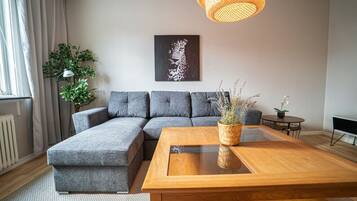 Ein modernes Wohnzimmer mit einem Ecksofa, einem Holztisch und einem Gemälde an der Wand.