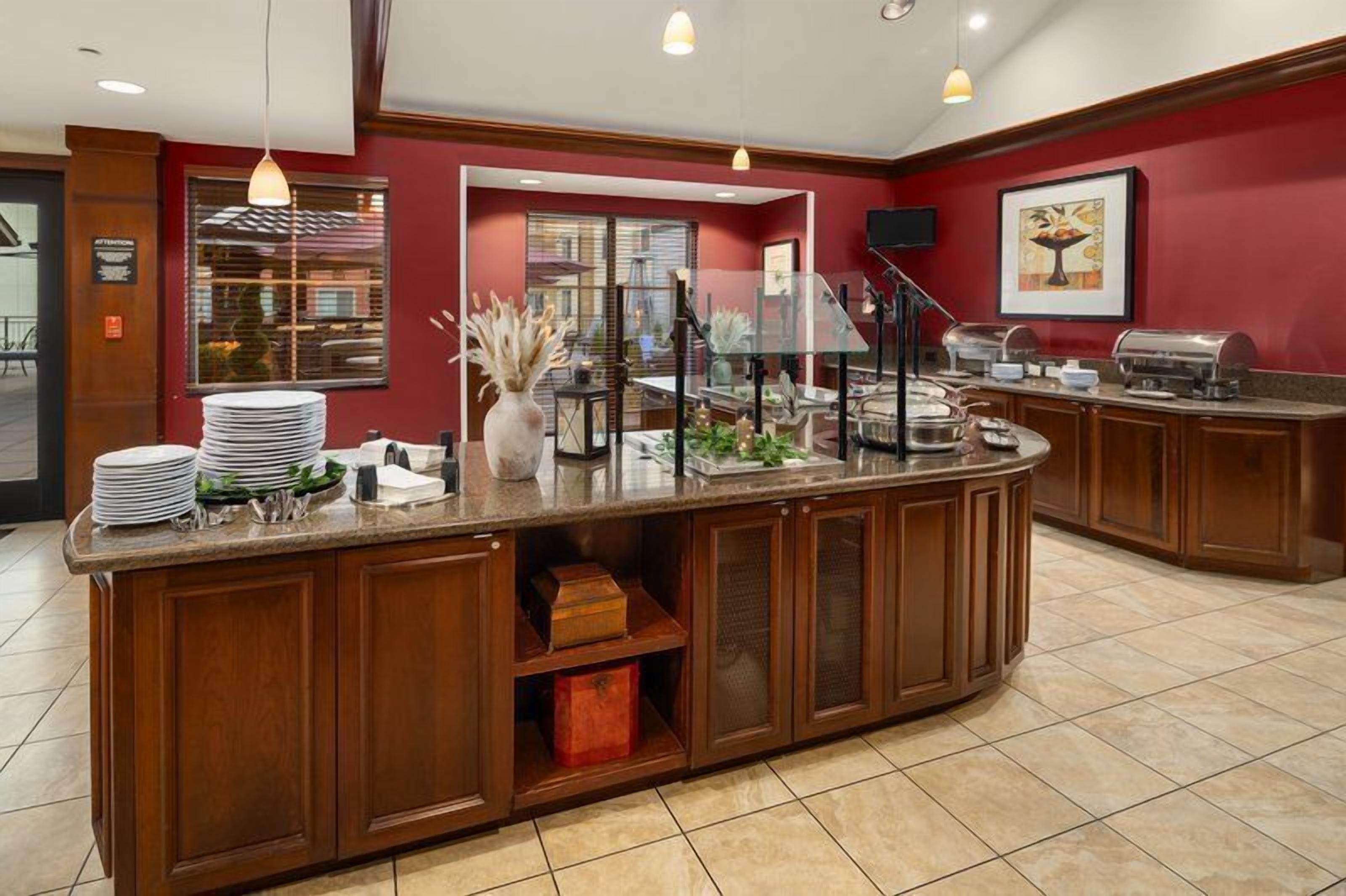 A buffet area with a counter, stacked plates, and a variety of food items.