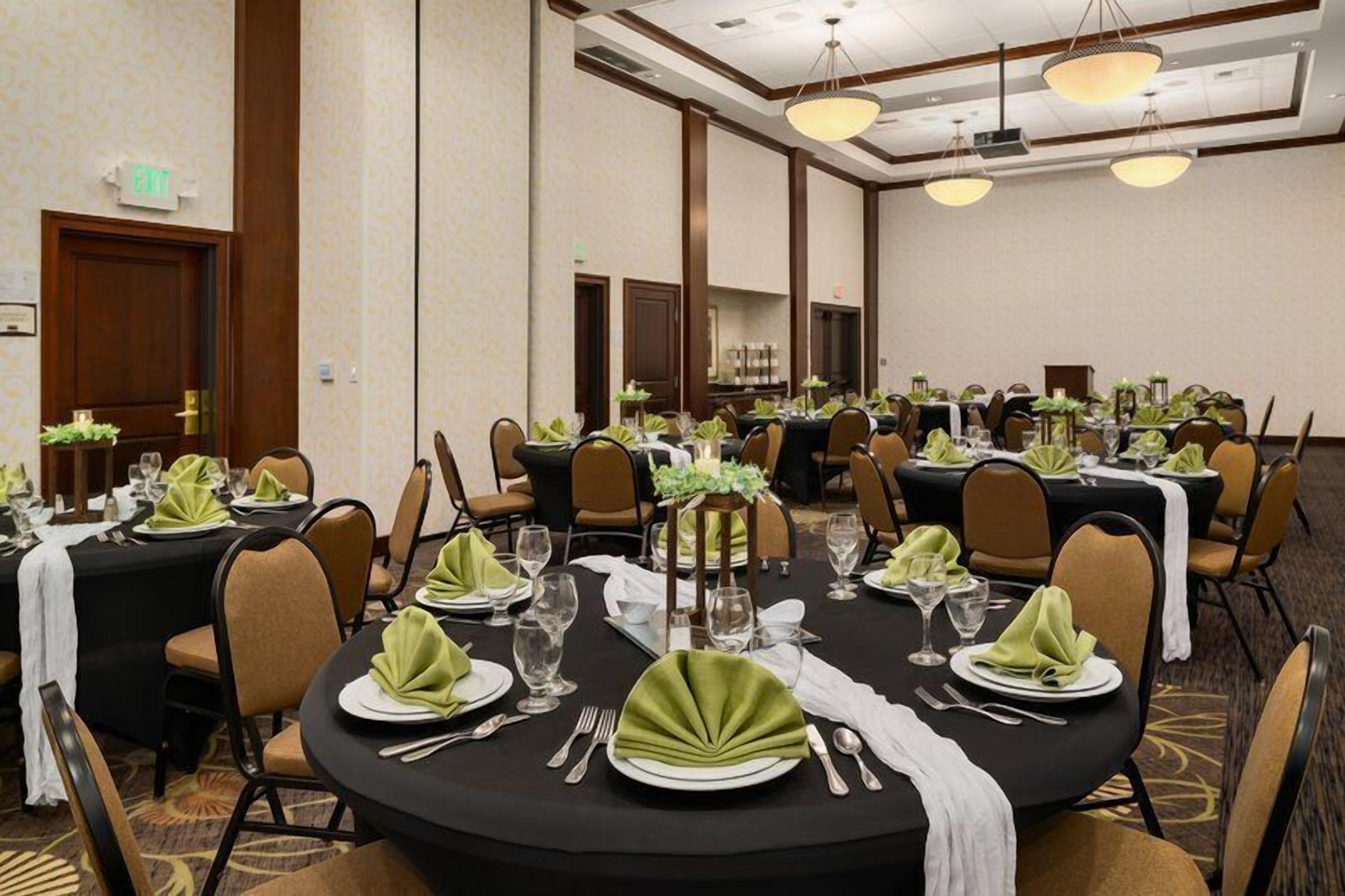 A conference room with round tables set for dining, equipped with chairs, tablecloths, and centerpieces.