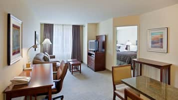 A hotel room with a desk, chair, television, and a bed with a view.