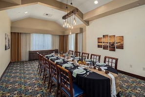 A conference room with a long table, chairs, and a carpeted floor.