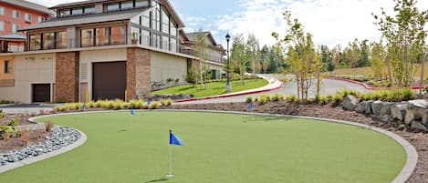 Un quartier résidentiel comprenant un terrain de golf, un immeuble avec un garage et une allée aménagée.