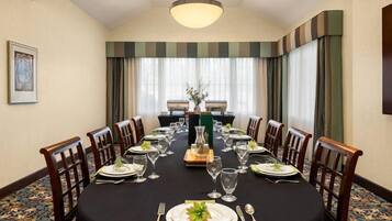 A conference room with a long table set for a meeting, surrounded by chairs, with a chandelier above.