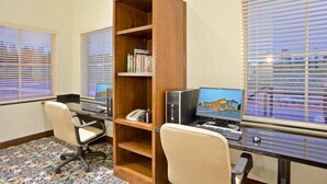 A room with two desks, a bookshelf, and a window with blinds.