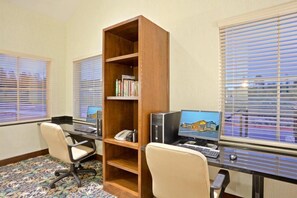 A room with two desks, a bookshelf, and a window with blinds.