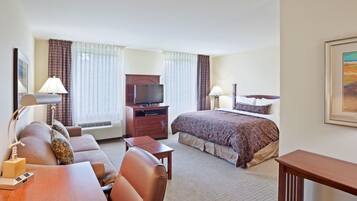 A hotel room with a bed, a desk, a television, and a lamp.