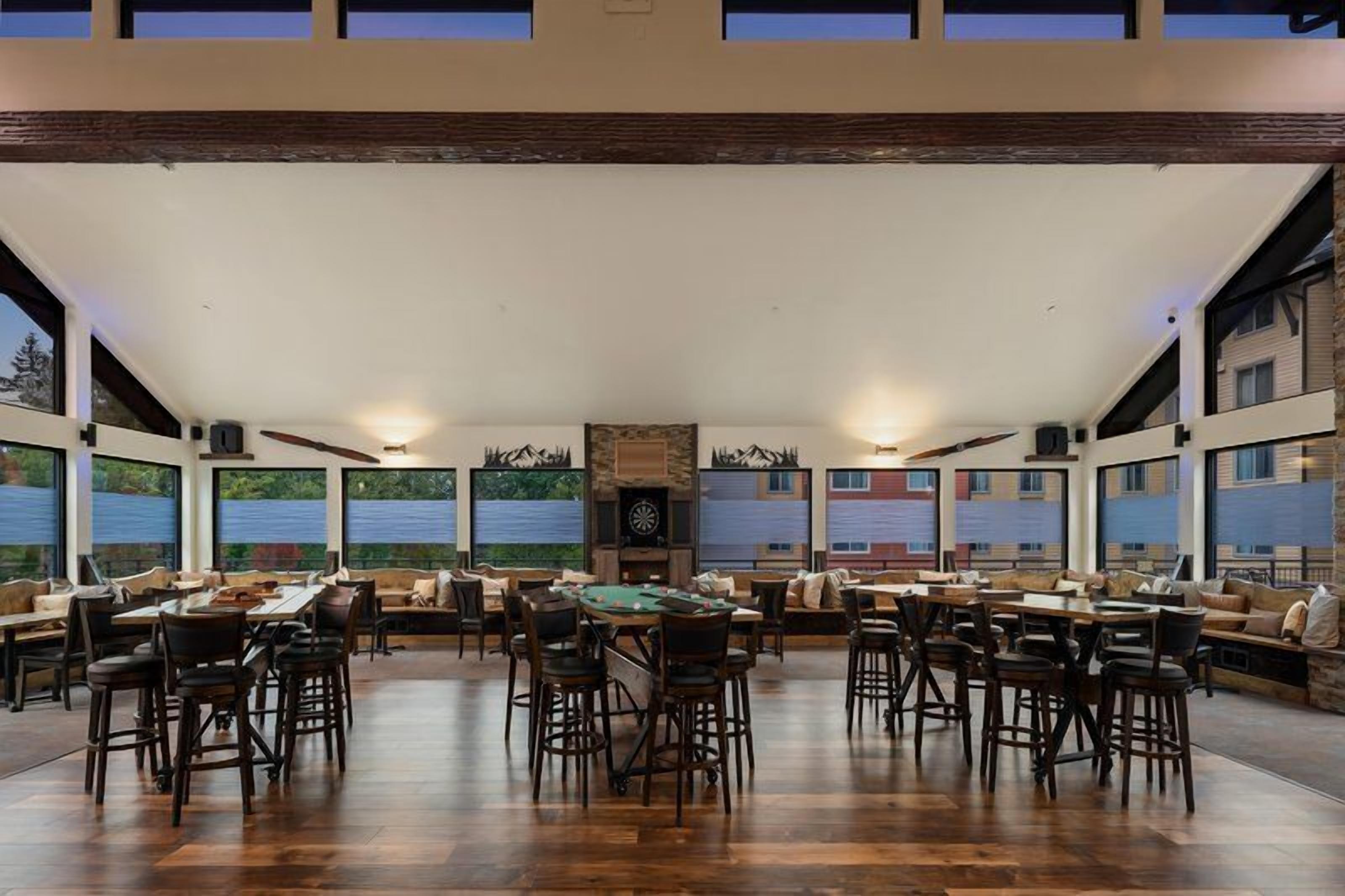 A spacious indoor area with a pool table, multiple seating arrangements, and large windows offering a view of the outdoors.