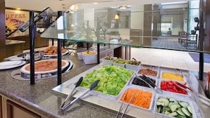 A buffet with various food options including salads, fruits, and vegetables.