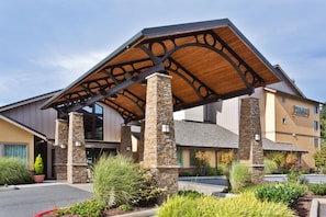 A hotel with a covered entrance, stone pillars, and a sign for 'Staybridge Suites'.