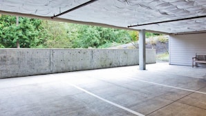 An empty parking garage with concrete floors and walls, a bench, and a covered area with a roof.