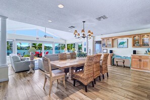 A spacious dining area with a high ceiling, natural light, and a view of the outdoors. - WTFR Home with pool, golf cart, large yard (Indian Rocks Beach)