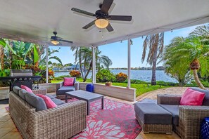 An outdoor patio with wicker furniture, a ceiling fan, and a view of the water. - WTFR Home with pool, golf cart, large yard (Indian Rocks Beach)