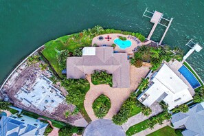 Vue aérienne d’un complexe hôtelier doté d’une piscine, d’un espace couvert et d’un quai.
