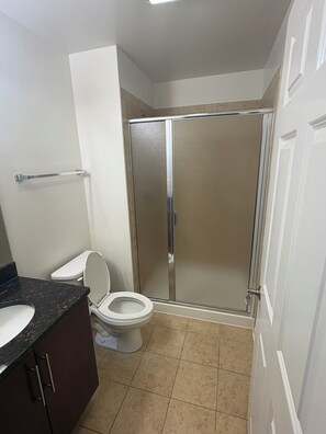 Une salle de bain comprenant des toilettes, un espace douche et un lavabo.