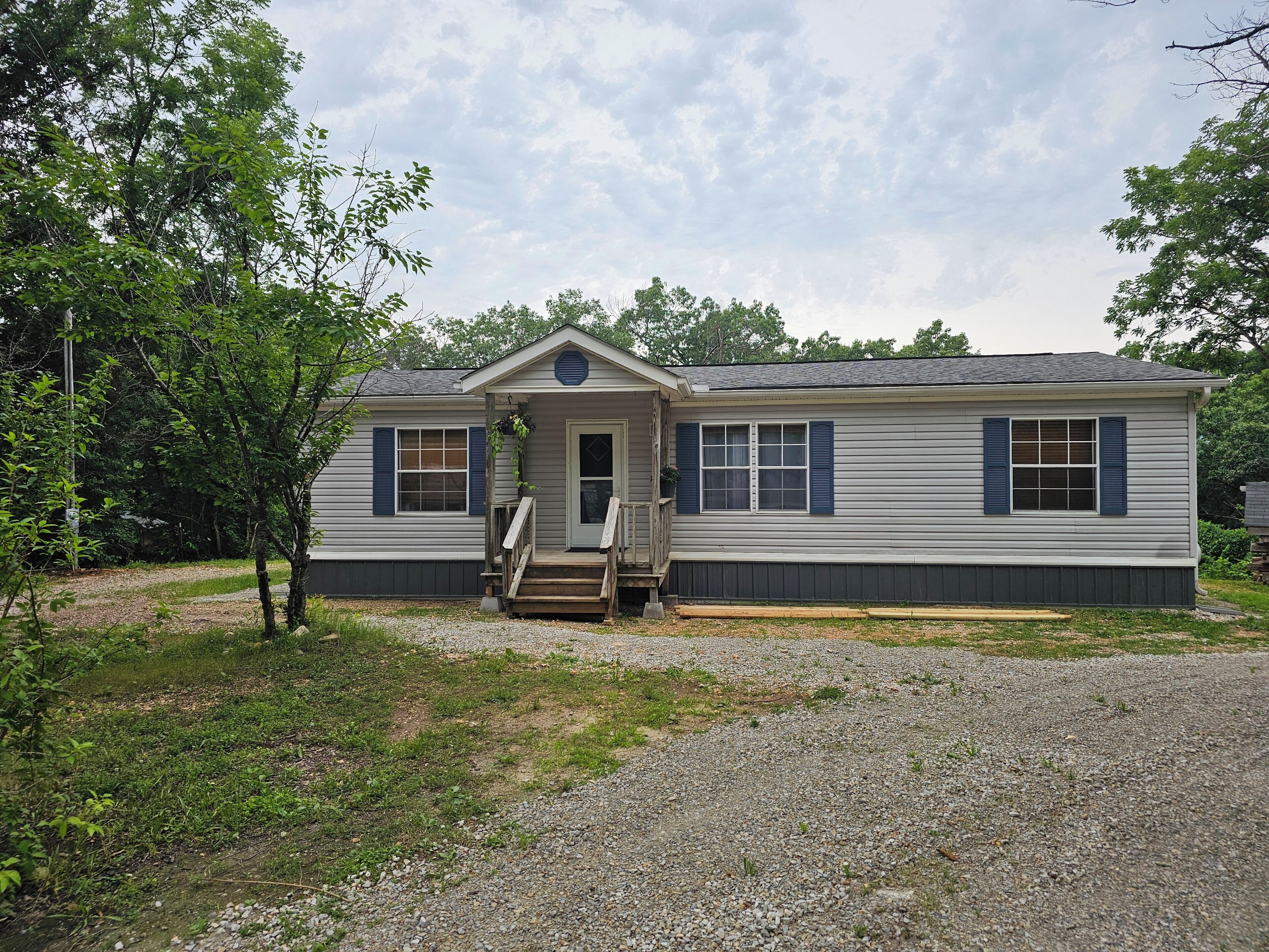 A single-story house with a front porch, a small entryway, and a gravel driveway.