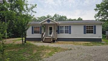 A single-story house with a front porch, a small entryway, and a gravel driveway.