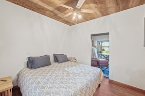 Ein Schlafzimmer mit einem Bett, einer Holzbalkendecke und Blick ins Freie.