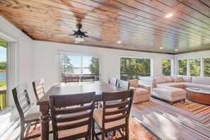 A spacious room with a dining table, chairs, a sofa, and a ceiling fan.