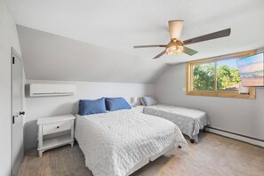 Une chambre avec deux lits, un ventilateur de plafond, une fenêtre avec vue et un appareil de climatisation.