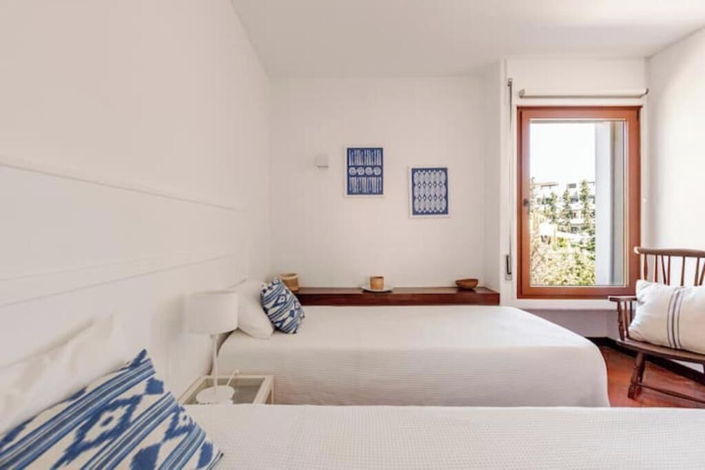 A room with two beds, a window with a view, and wall-mounted decor.