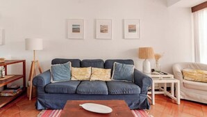 A living room with a blue sofa, a wooden coffee table, and a white lamp. - Balaia Apartment: BEACH and GOLF (Albufeira)