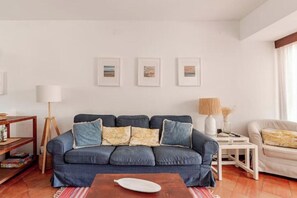 A living room with a blue sofa, a wooden coffee table, and a white lamp. - Balaia Apartment: BEACH and GOLF (Albufeira)