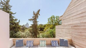A bench with cushions in a courtyard with trees and a building in the background. - Balaia Apartment: BEACH and GOLF (Albufeira)