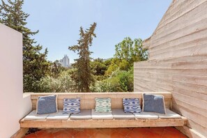 A bench with cushions in a courtyard with trees and a building in the background. - Balaia Apartment: BEACH and GOLF (Albufeira)