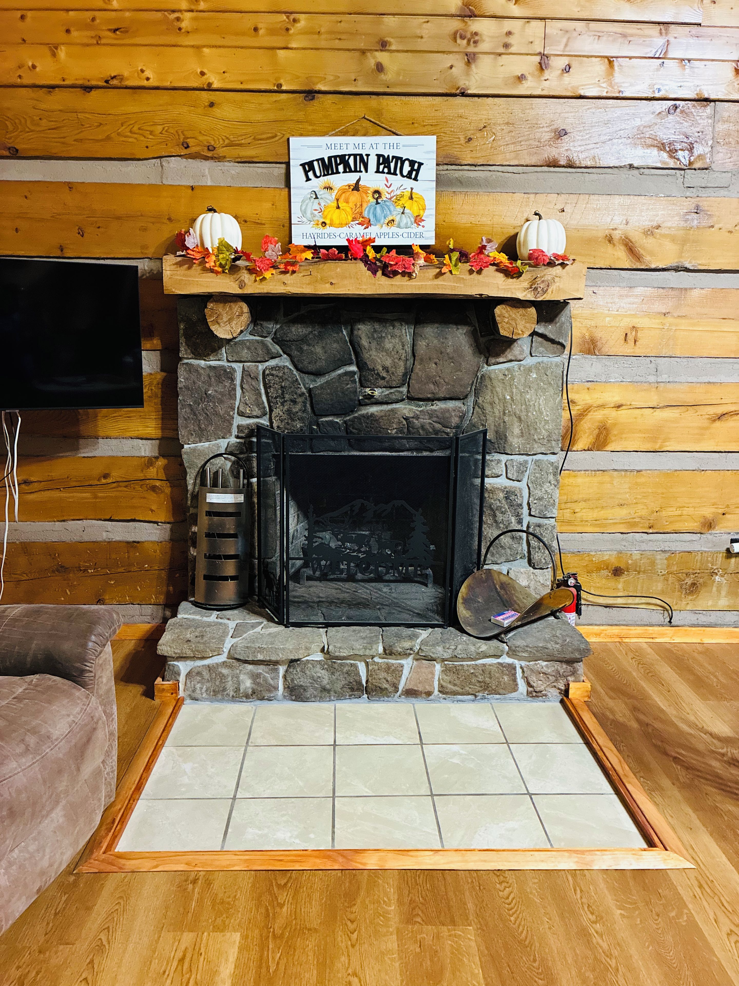A fireplace with a sign above it, a television mounted on the wall, and a cushioned seating area.