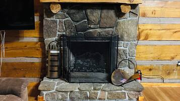A fireplace with a sign above it, a television mounted on the wall, and a cushioned seating area.
