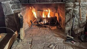A stone fireplace with a fire burning inside, surrounded by stone walls.