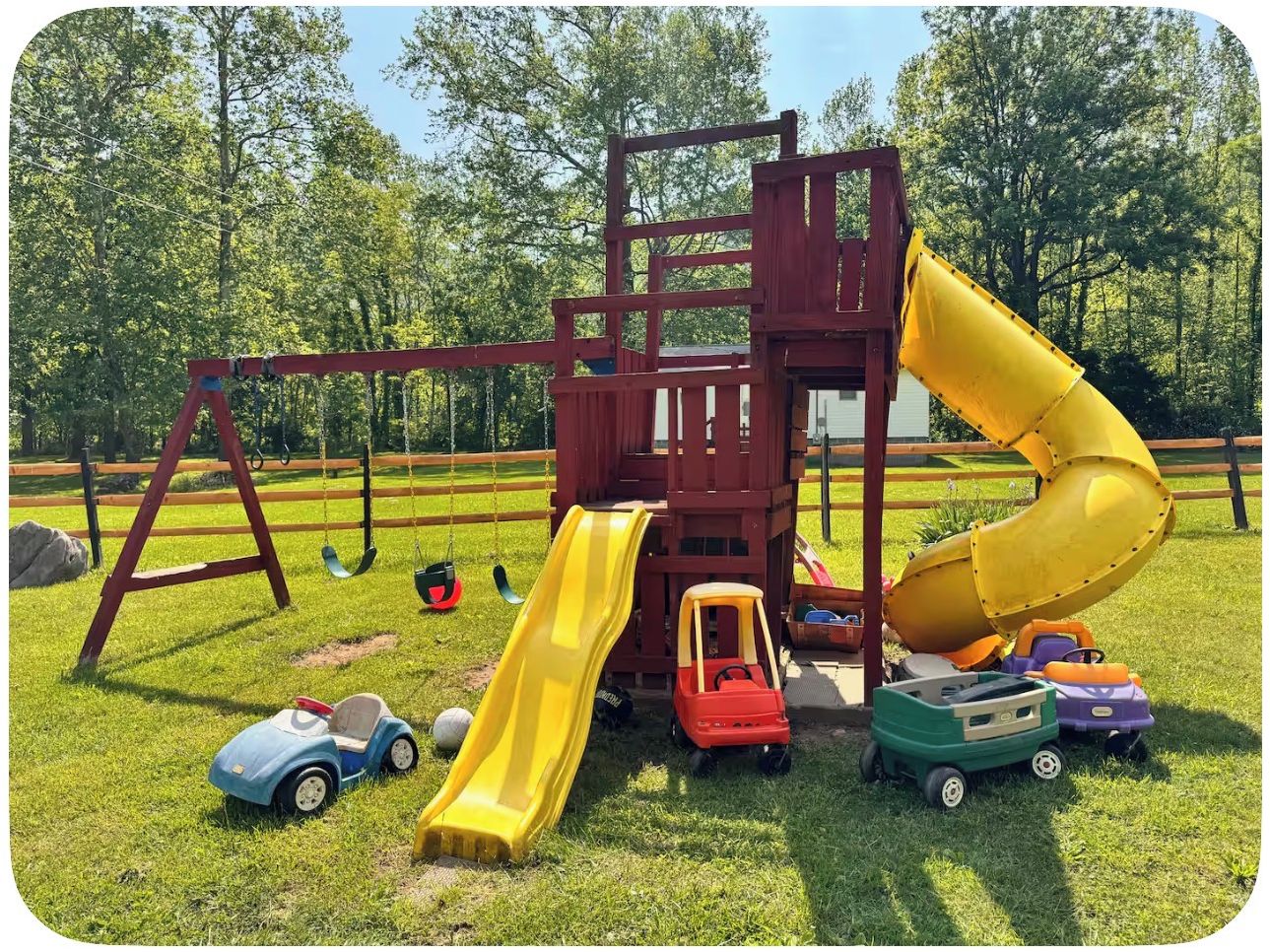 Ein Spielplatz mit Rutsche, Schaukeln und Spielzeugautos.