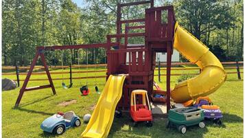 Ein Spielplatz mit Rutsche, Schaukeln und Spielzeugautos.