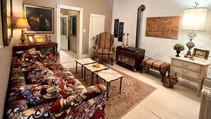 A living room with a sofa, coffee table, fireplace, and a white brick wall. - Vulture's Roost (Makanda)
