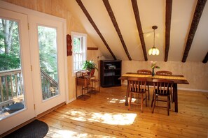 A wooden interior with a dining table, chairs, a bookshelf, and a potted plant. - Quietside Tree House - Peaceful 1-bedroom studio with AC in Acadia Mount Desert (Mount Desert)
