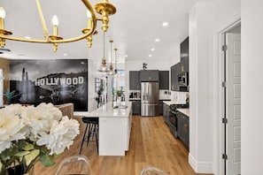 A modern kitchen with a central island, stainless steel appliances, and a decorative chandelier. - Red Rock Retreat - 4BR - Hot Tub - Fire Pit (Hurricane)