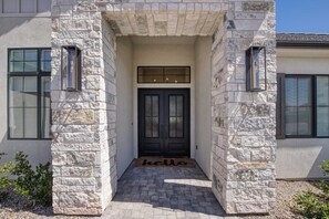 A stone facade entrance with a black door and a 'hello' mat. - Red Rock Retreat - 4BR - Hot Tub - Fire Pit (Hurricane)