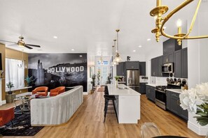 A modern kitchen with dark cabinets, stainless steel appliances, and a white island. - Red Rock Retreat - 4BR - Hot Tub - Fire Pit (Hurricane)