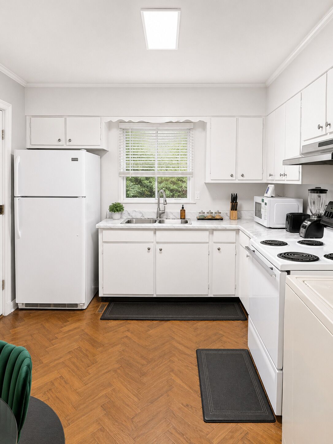 A modern kitchen with white cabinetry, a built-in stove, a microwave, and a refrigerator.