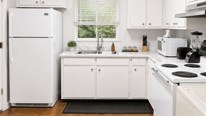 Una cocina moderna con armarios blancos, estufa integrada, microondas y refrigerador.