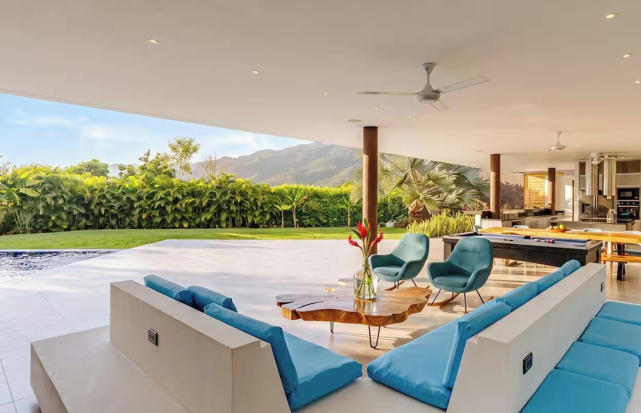 Ein modernes Wohnzimmer mit Pool, blauem Mobiliar und Blick auf Berge.