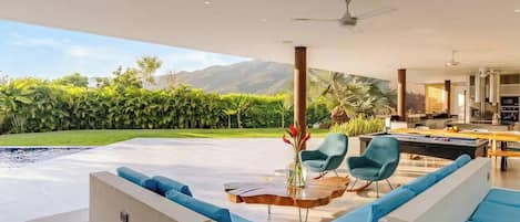 Un salon moderne avec une piscine, des meubles bleus et une vue sur les montagnes.